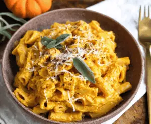 Creamy Parmesan Pumpkin Pasta served on a white plate, garnished with fresh herbs, showcasing an easy and delicious fall-inspired recipe
