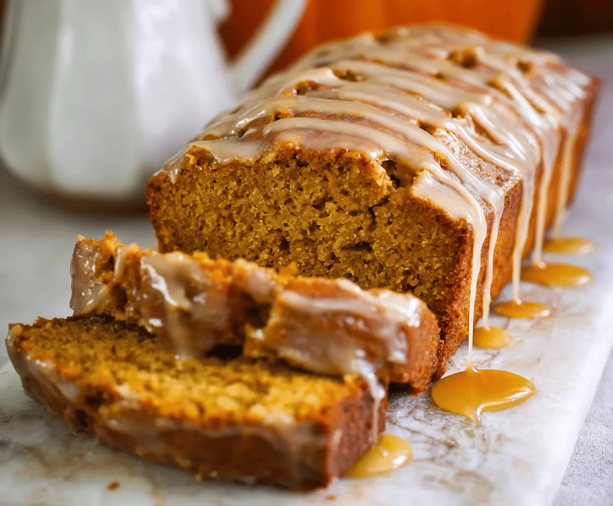 Delicious homemade pumpkin bread topped with a glossy maple glaze, served on a rustic wooden platter with cinnamon sticks and a cup of coffee.