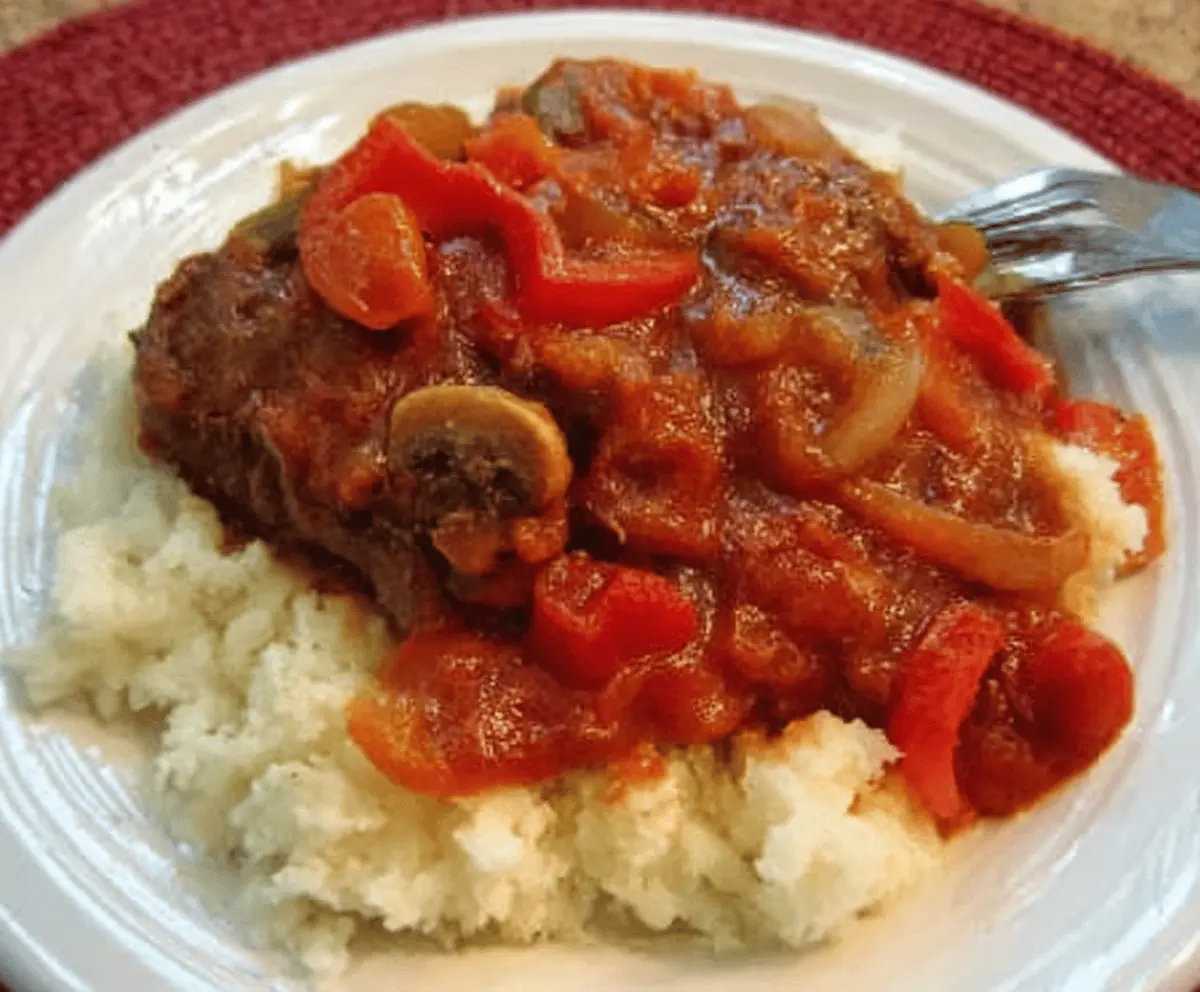 Delicious Easy Swiss Steak served on a plate with vegetables and gravy.