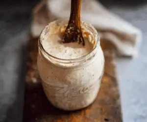 A step-by-step photo guide showing how to make a healthy sourdough starter with flour and water in a glass jar for homemade bread baking.