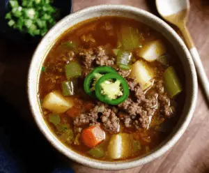 Delicious Mexican ground beef stew with spicy jalapeños and flavorful herbs, served in a bowl with fresh toppings.