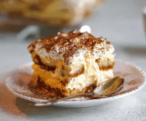 Delicious Pumpkin Chai Tiramisu served in a glass dish with layers of creamy mascarpone, spiced pumpkin, and chai-flavored ladyfingers, perfect for fall desserts.