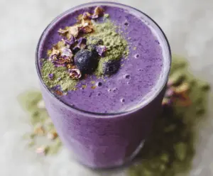 Creamy wild blueberry vanilla matcha smoothie in a glass with fresh blueberries, vanilla bean, and matcha powder for a healthy breakfast or snack