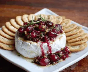 Delicious Baked Brie with Cranberries on a serving platter, garnished with fresh herbs