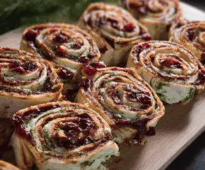 Delicious spicy turkey and cranberry pinwheels garnished with fresh herbs on a serving plate.