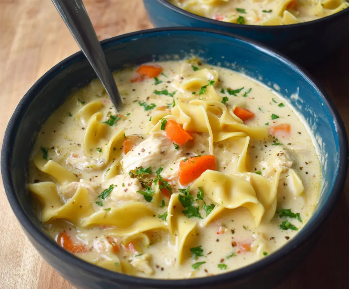 Delicious and easy creamy chicken noodle soup in a bowl with fresh herbs