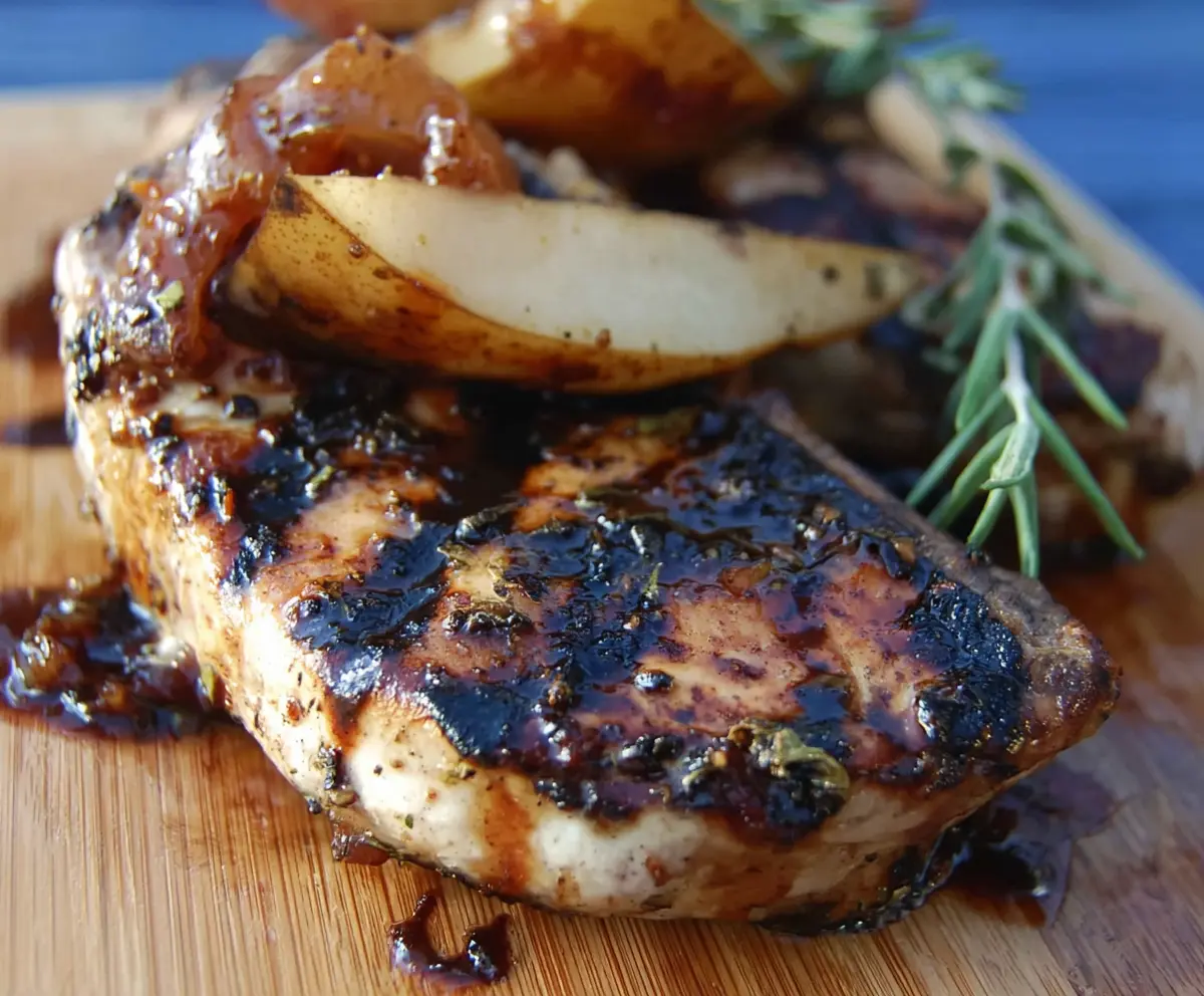 Juicy grilled pork chops served with sweet balsamic caramelized pears on a plate.