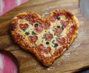 Delicious Valentine Pizza topped with heart-shaped pepperoni and fresh vegetables for a romantic dinner.